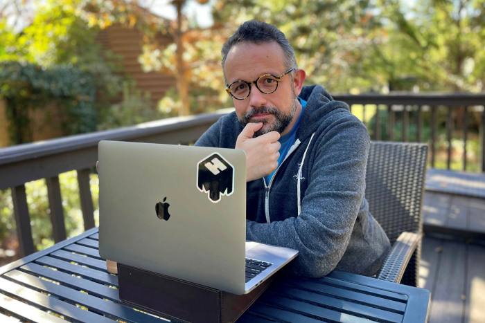 Phil Libin, cofounder and CEO of mmhmm, sits at a wooden table on an outside deck with his laptop open in front of him