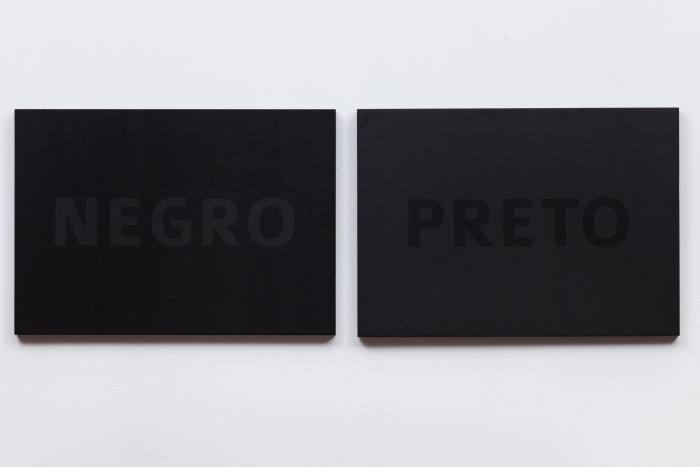 Two almost black silk-screen canvases side by side, one with the word ‘Negro’, one with ‘Preto’