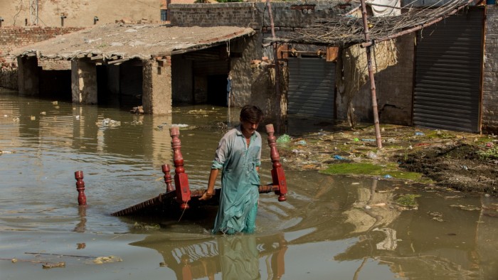 A man carries furniture through floodwater at Goth Muhammad Yusuf Naich in Dadu district, Sindh province, Pakistan