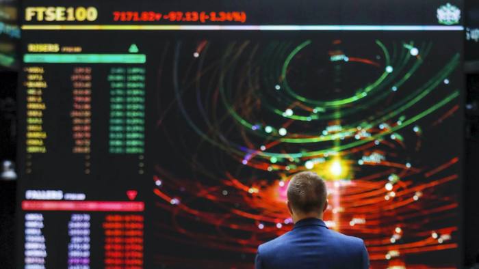 An employee views a FTSE share index board at the London Stock Exchange 