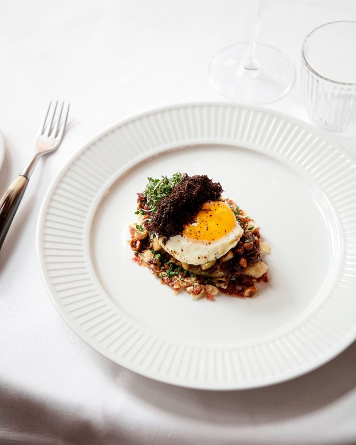  A plate of Thøstesen’s signature fried-egg dish, served on potato purée with truffle, duck confit, truffle sausage, hazelnuts, croutons and grated truffle