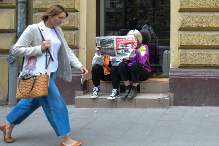 People sitting outside a shop seen reading today’s ‘Dziennik Polski’ newpaper with on the front page