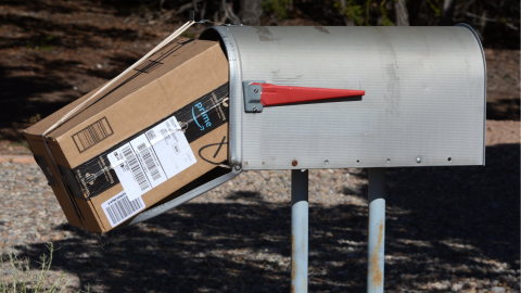 An Amazon boxed package wedged into a mailbox