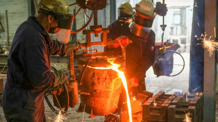 Foundry workers pour molten iron into moulds