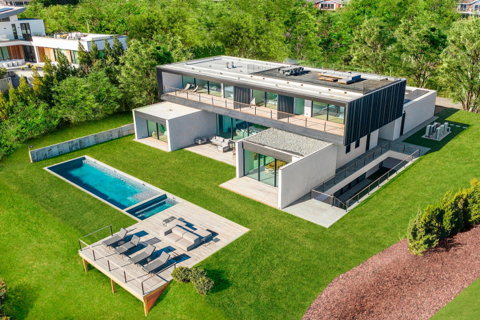 Aerial view of modern white and grey compound with pool area and space for pool loungers by the side