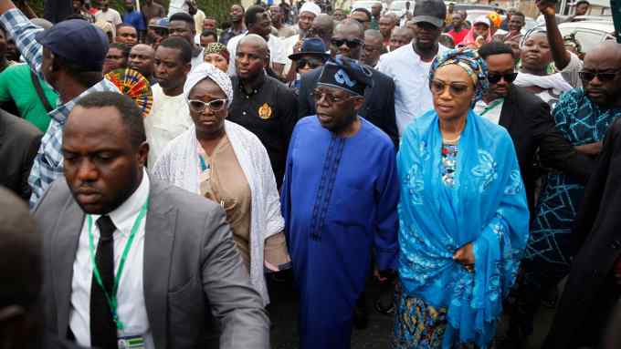 Presidential candidate Bola Tinubu makes his way through a crowd after casting his vote at a polling station in Lagos