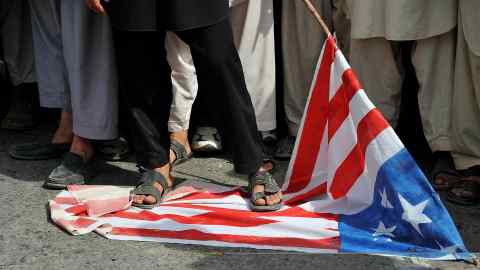 Afghan demonstrators stand on a US flag during a 2013 protest in Jalalabad