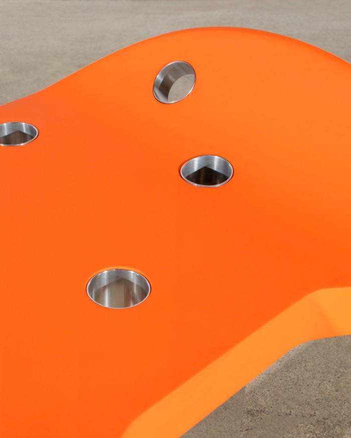 Close-up of an orange bench with steel-lined holes