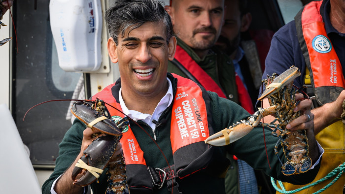Prime Minister Rishi Sunak holds two lobsters while campaigning at the fishing harbour of Clovelly in Devon