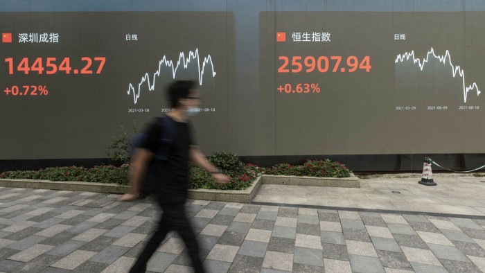 A man in Shanghai  walks past a screen on the side of a street displaying stock exchange figures. When Shanghai, Shenzhen and Hong Kong are taken in combination, they represent the world’s second largest global equity market