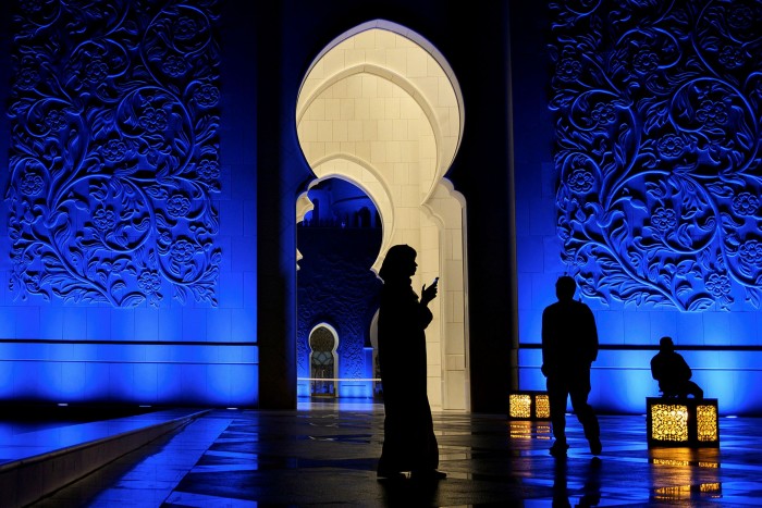 A woman looks at her phone in Sheikh Zayed Grand Mosque in Abu Dhabi. The UAE authorities have been accused of using surveillance to monitor domestic critics and opponents