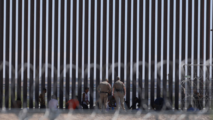 Migrants seeking asylum in the US are watched by Texas agents next to the border wall in El Paso