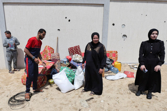 Displaced Palestinians who fled Rafah after the Israeli military began evacuating civilians stand next to their belongings, in Al-Mawasi area 