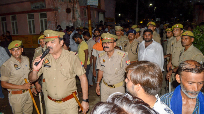 Policemen manage the mourners as bodies are brought a hospital in Hathras in Uttar Pradesh 