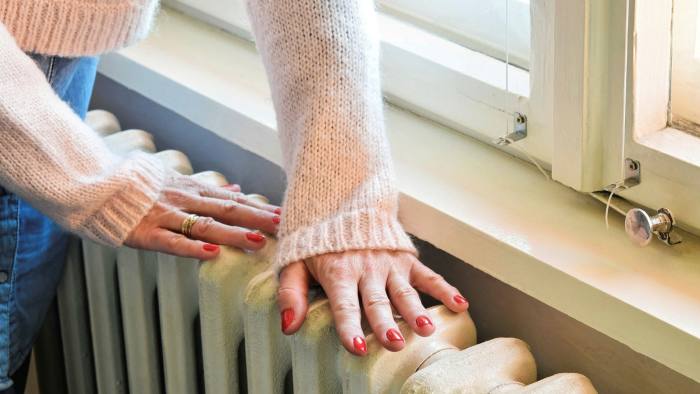 A woman puts her hands on a metal radiator