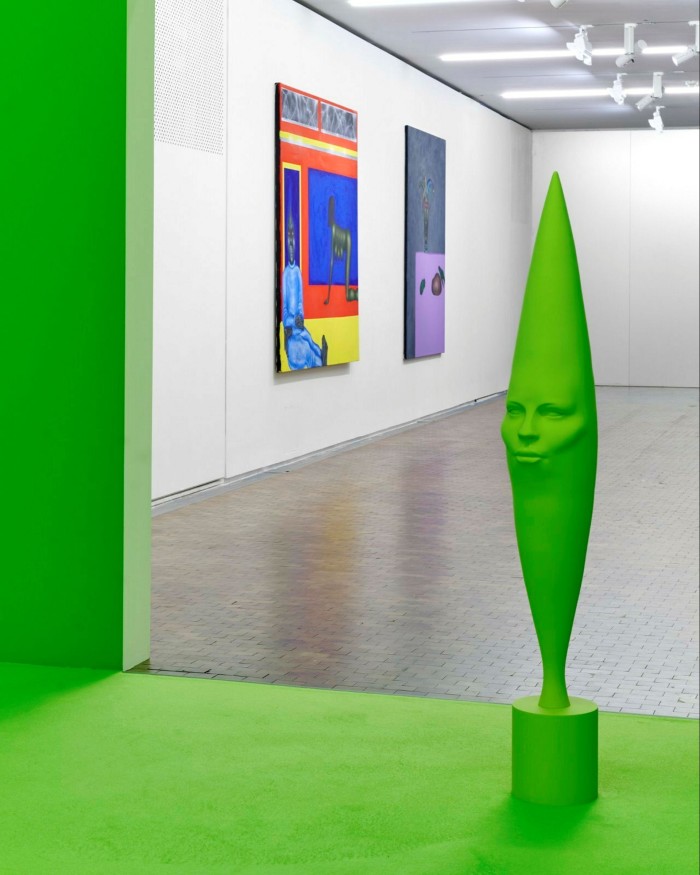 A lime-green sculpture like a bowling in stands in a gallery