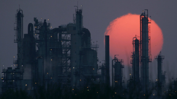 A US oil refinery silhouetted against the setting sun