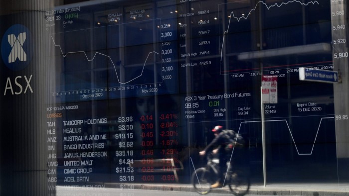 A cyclist is reflected in a window of the Australian Securities Exchange
