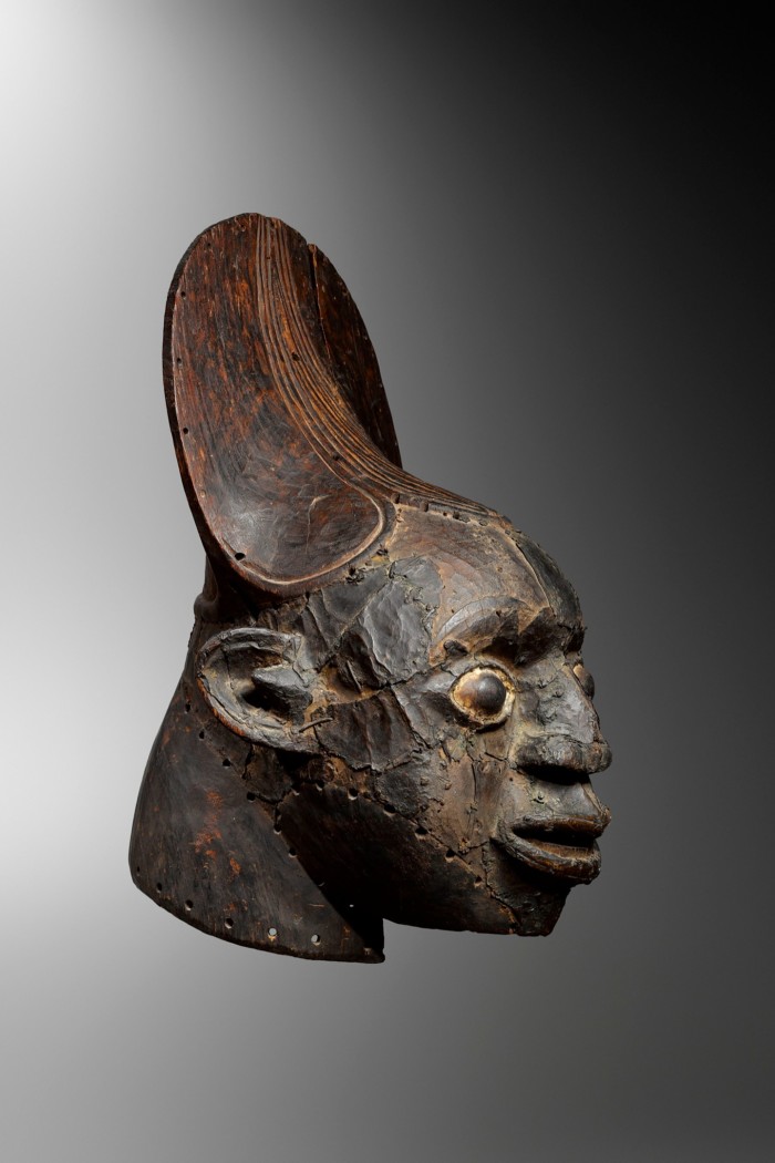 Wooden head of a man plated with copper. He is wearing a crown which looks like a flat mirror