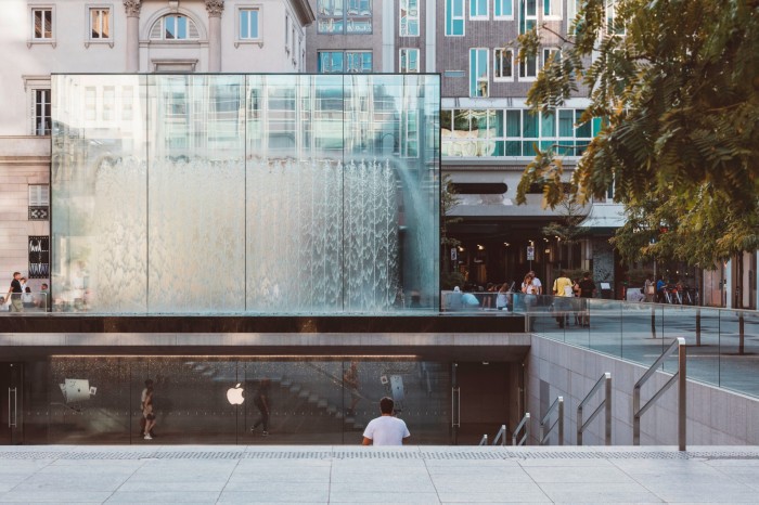 The top of the stairs leading down to the Apple store on Piazza Liberty, with the square glass structure of its fountain protruding at the top