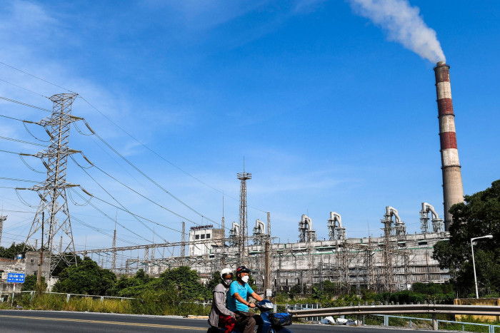 Two people riding a motorbike past Pha Lai thermal power plant in Hai Duong province