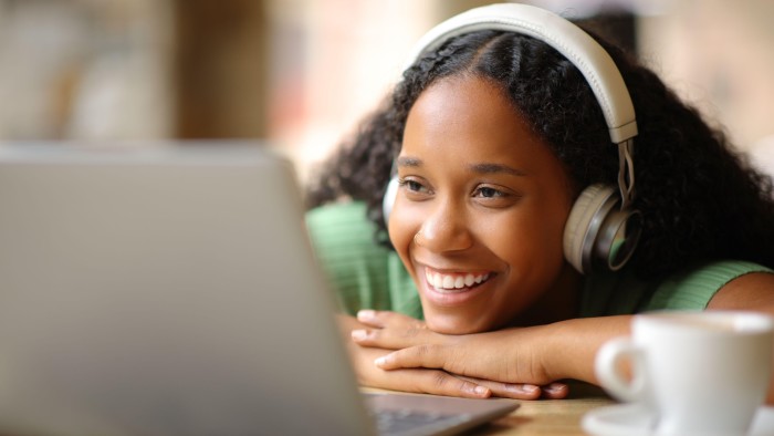 A young woman wearing headphones watching media on her laptop