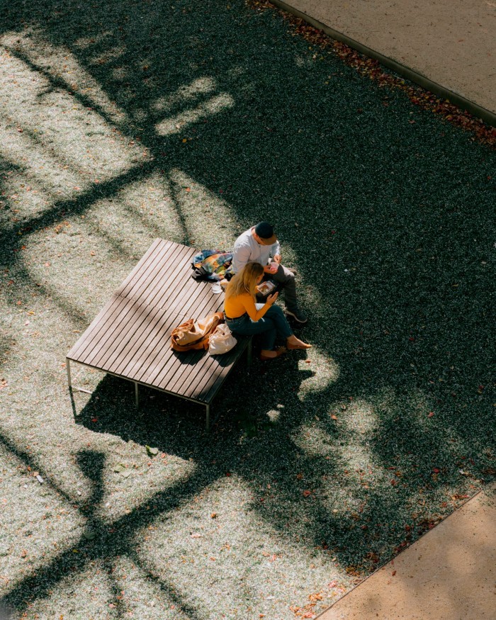  A man and a woman eating lunch at a table in the park, photographed from above