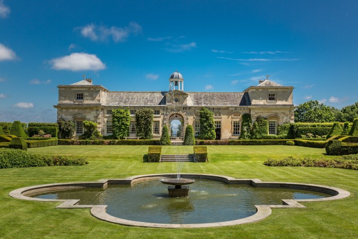 A water feature sits in front of a palatial country house