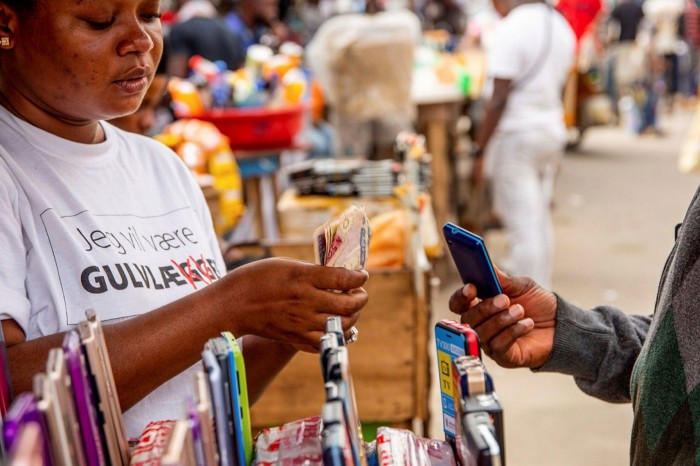 A vendor counts out Nigerian naira banknotes for the purchase of a second-hand mobile phone from a kiosk at the Ikeja computer village market in Lagos, Nigeria