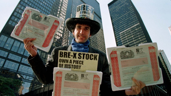 A man wearing a top hat holding stock certificates for Bre-X Minerals