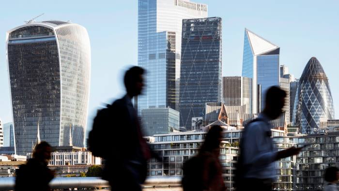 UK, London, blurred motion of incidental business people walking to work with view of the financial district behind