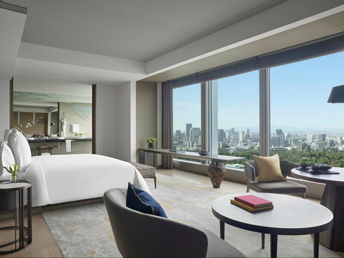 A white- and grey-hued guest room at Four Seasons Hotel Tokyo at Otemachi, looking through floor-to-ceiling windows over the cityscape below