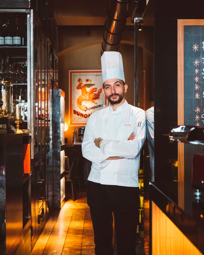 Langosteria executive chef Domenico Magistri, a bearded young man in chef’s whites and toques, standing in the restaurant
