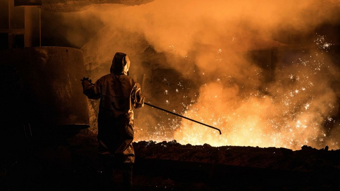 A worker oversees molten iron undergoing purification and alloying to become steel 