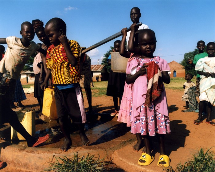 Children help collect water from the borehole pump