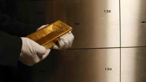 An employee holds a gold bar in the precious metals vault at Pro Aurum in Munich
