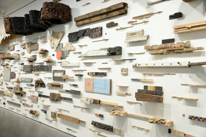 Flat wooden sculptures are stuck on a white wall