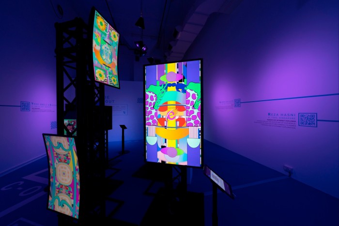 Bright abstract digital images on screens in a purple-darkened room 