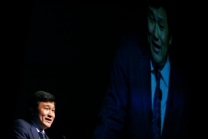 Li Lu in profile against the backdrop of a giant dark screen, speaking at an investment conference in New York in May 2013