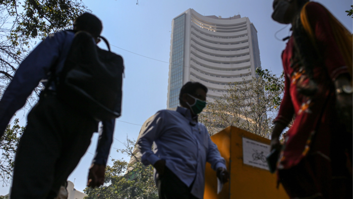 Pedestrians wear masks walking by the Bombay Stock Exchange