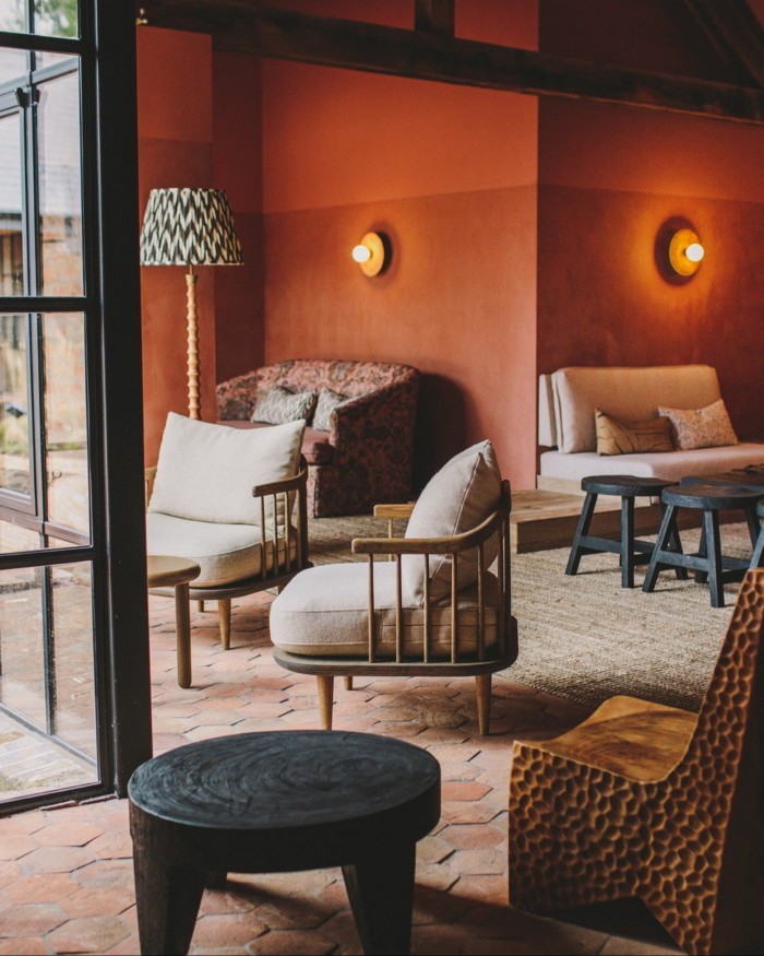 Cream sofas and chairs at terracotta-coloured walls in Grace & Savour’s lounge