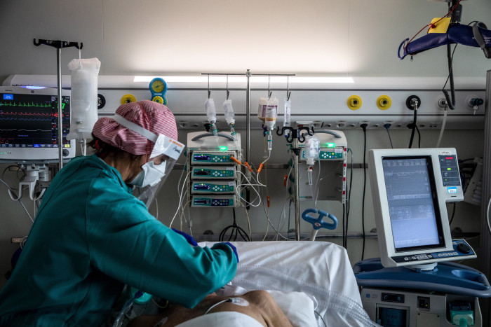 A nurse treats a patient on a ventilator in an intensive care unit 