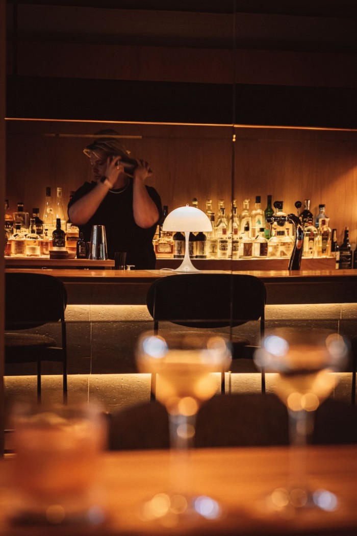 The dimly lit Héroine restaurant, with a bartender holding a cocktail shaker 