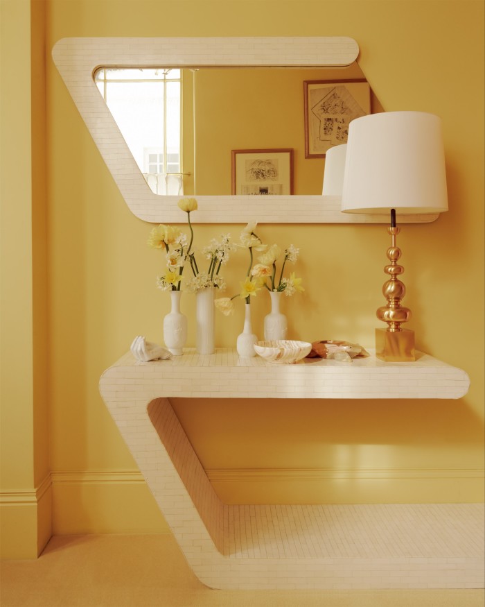 A vintage Ron Seff tessellated bone mirror and matching console table in the sherbet-lemon hallway. The ’70s gold lamp is from Pamono