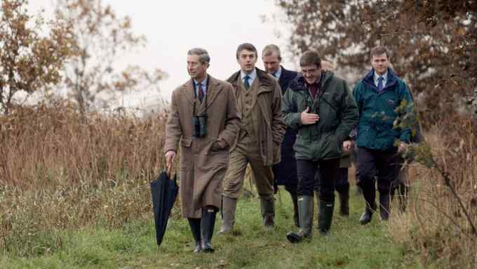 A group of men walk in the countryside wearing wellington boots
