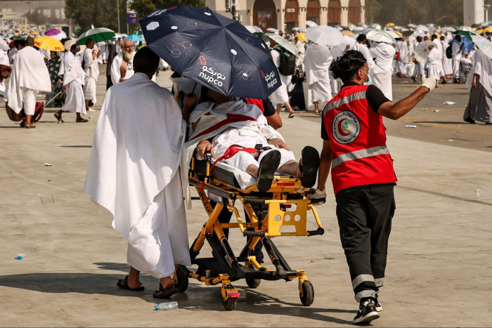 A medical team evacuates a pilgrim, affected by the soarching heat at the base of Mount Arafat during the annual hajj 