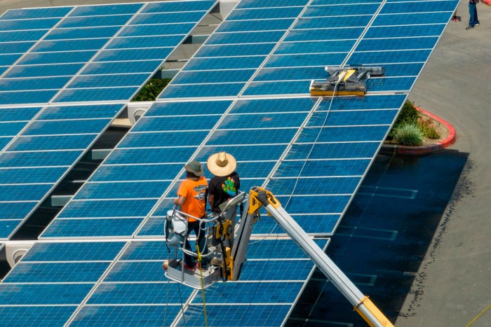 workers using a robot to clean solar panels