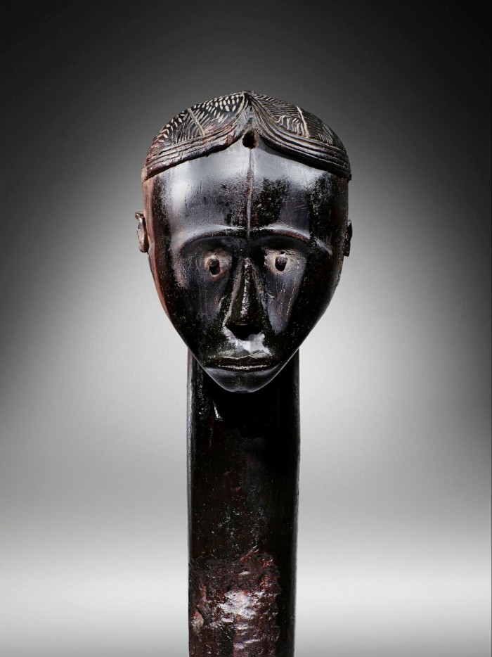 A black wooden head, looking serious, on a staff