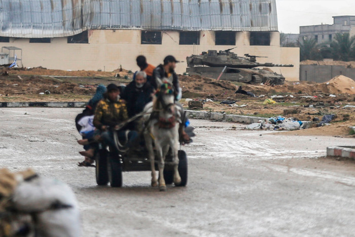 A cart carries a group of Palestinians past an Israeli tank near Nasser hospital
