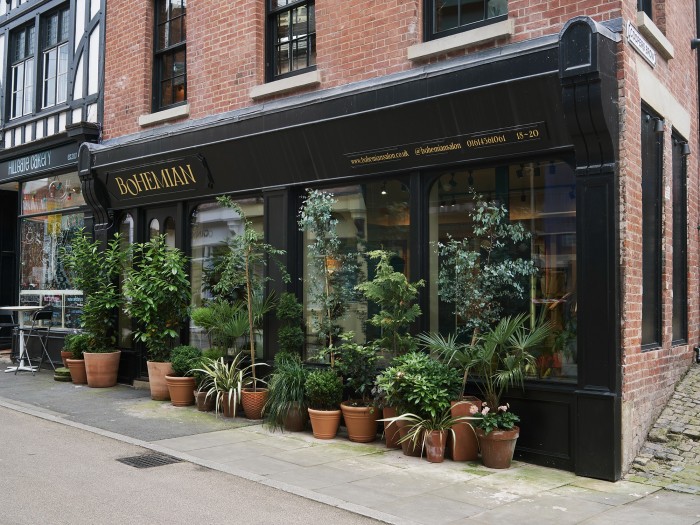 A glass fronted business with potted plants positioned along the front